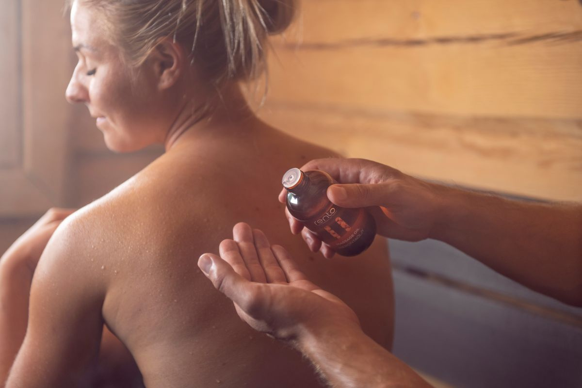 en dam med ryggen mot kameran och ett par händer med flaskan