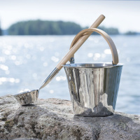 Bastuhink och Skopa i Rostfritt Stål Bastuhinken och skopan på en klippa vid vatten