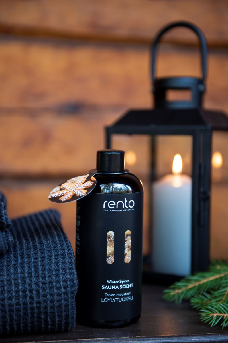 Bastudoften bredvid en handduk och gren framför en lykta med ett levande ljus