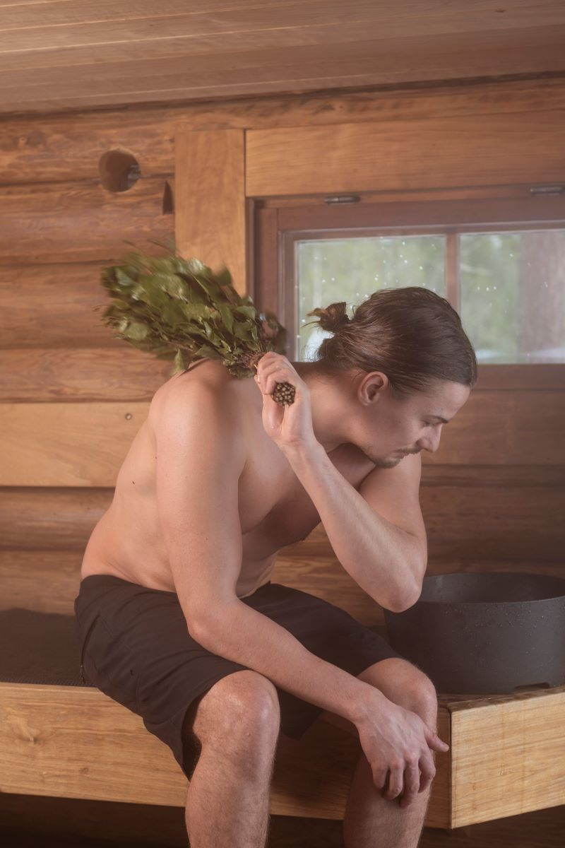 En man använder basturuskan i en bastu