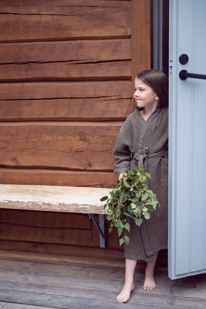 En flicka står i en dörröppning och håller i basturuskan 