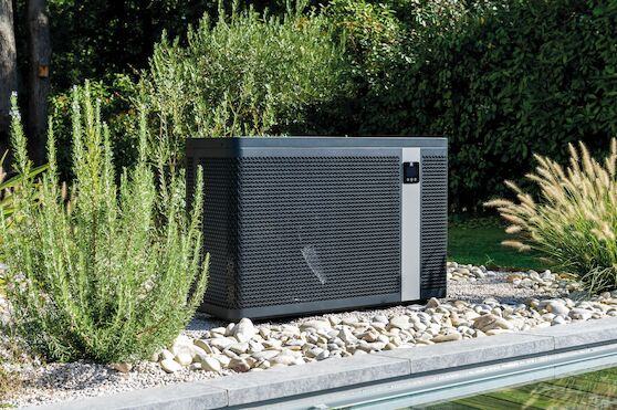 Luftvärmepumpen står bland buskar bredvid en pool